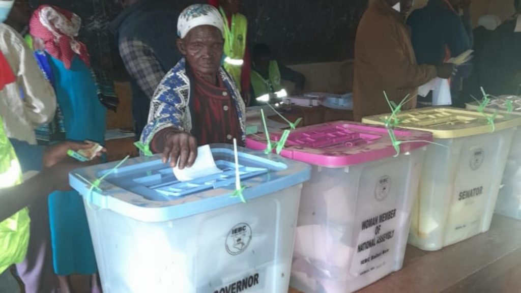 Frau steckt Wahlzettel in Wahlbox