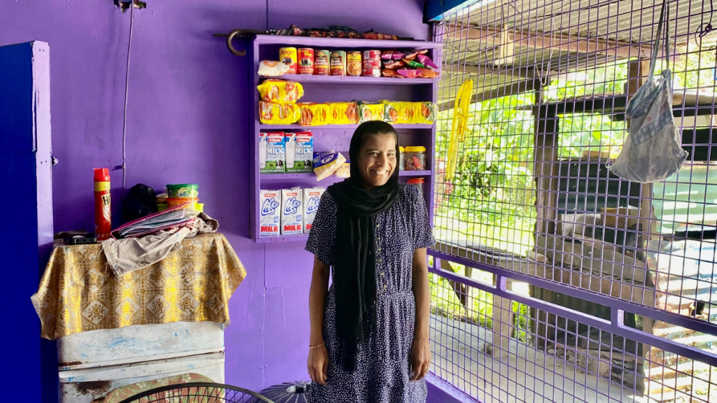 Frau vor Dorfladen mit lila Wand in Fidschi