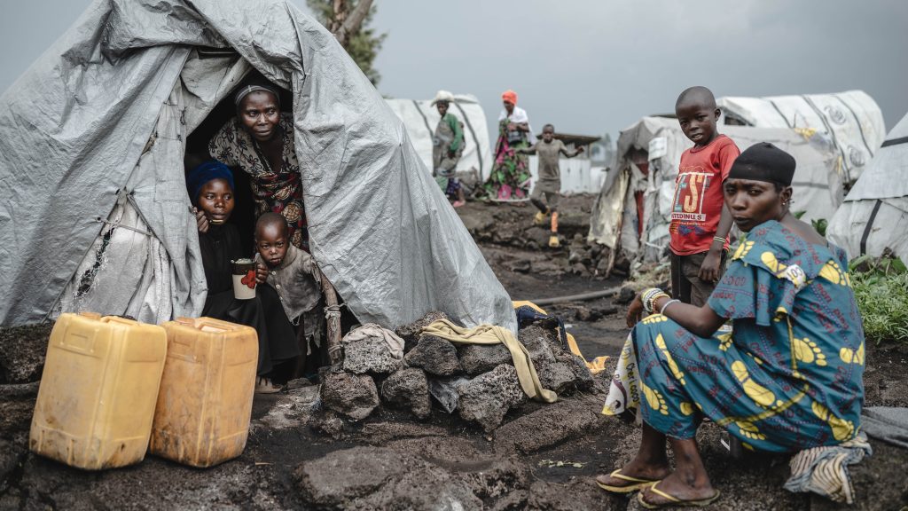 Frau sitzt mit ihren Kindern im Zelt eines Flüchtlingslagers